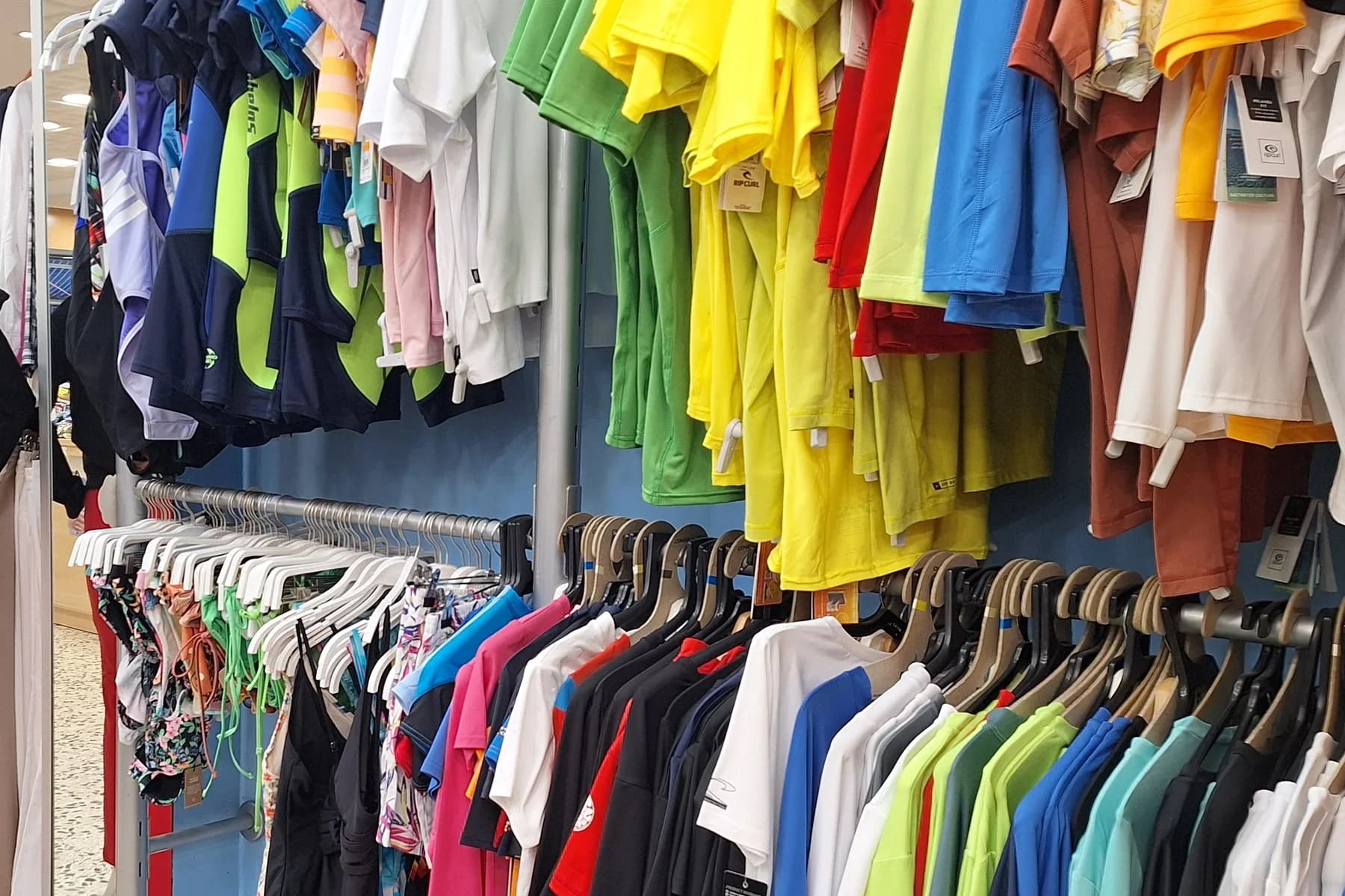Interior de loja esportiva com roupas esportivas coloridas expostas em araras