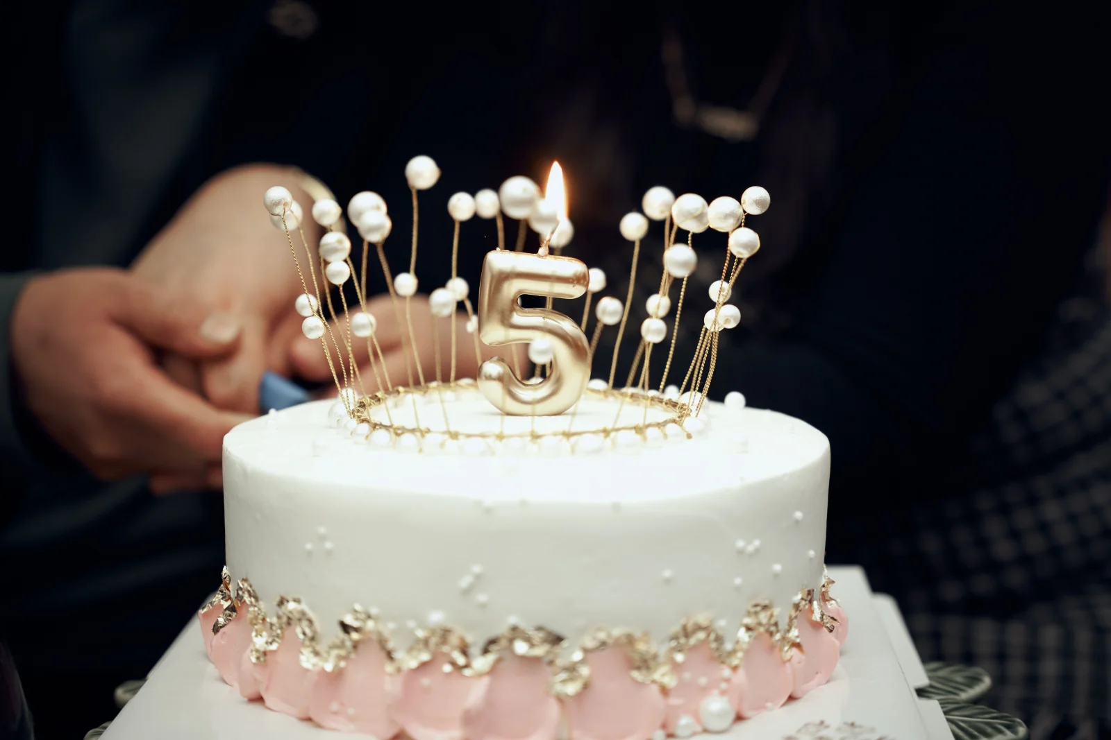 Vela dourada em formato de número 5 sobre um bolo de aniversário