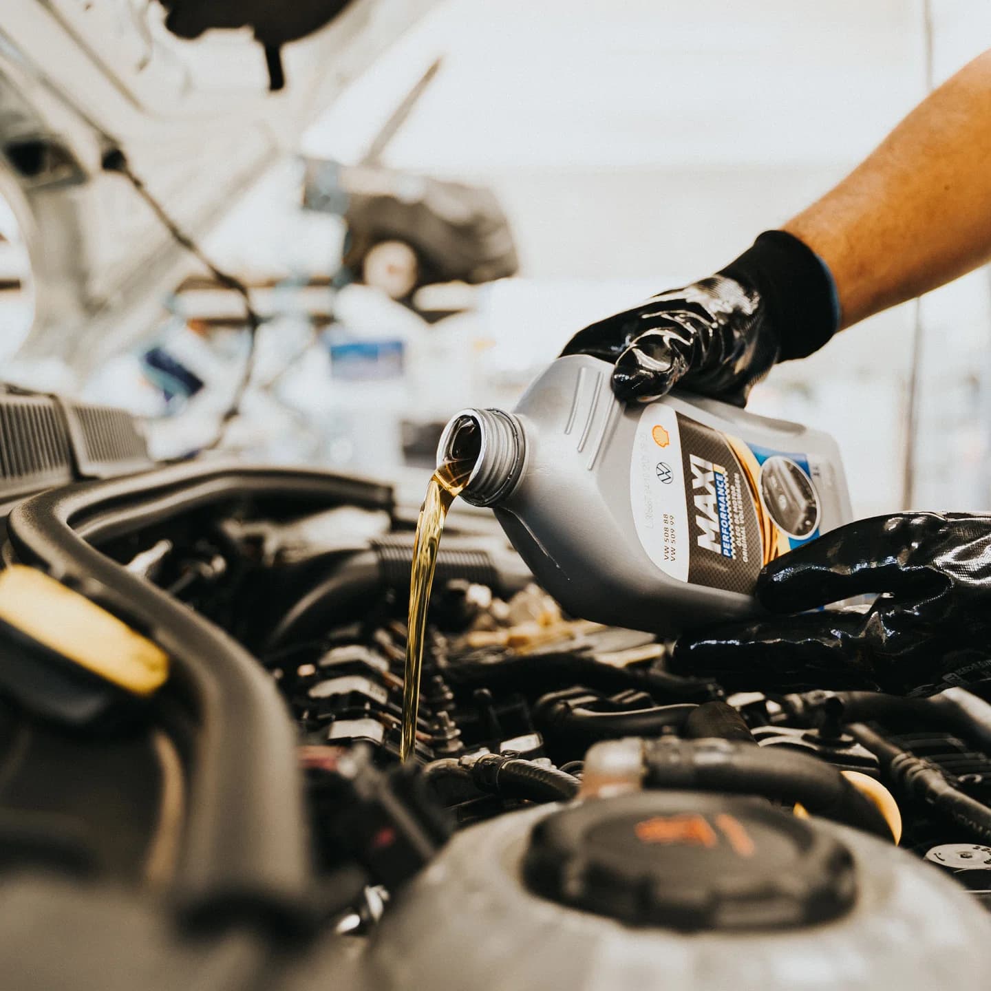Mecânico abastecendo óleo lubrificante no motor de um carro