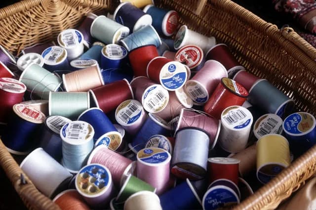 Cesta com carretéis de linha de costura em várias cores