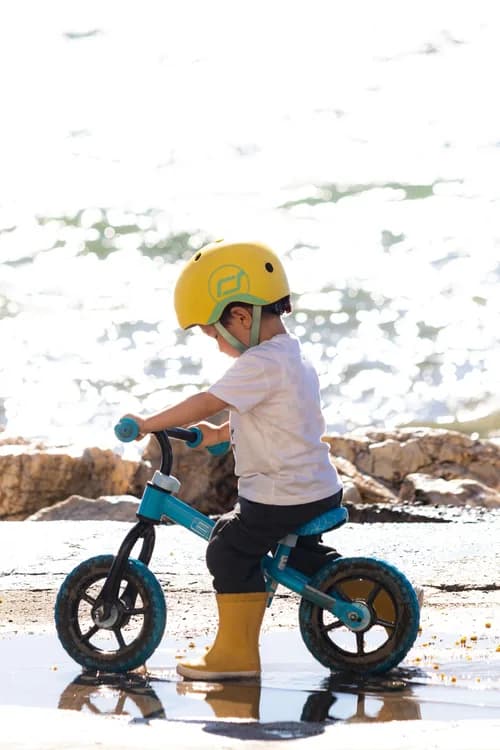 Criança usando uma bicicleta infantil de equilíbrio à beira da água
