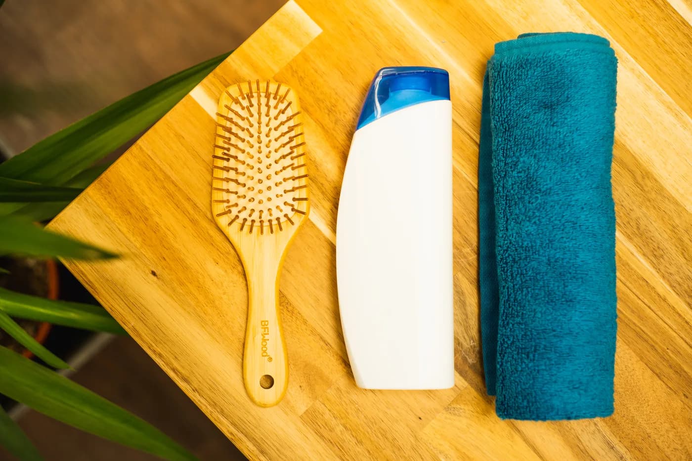 Frasco de shampoo sem rótulo ao lado de escova e toalha