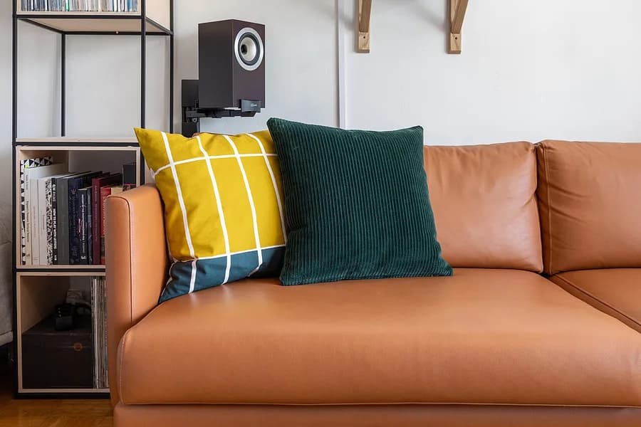 Duas almofadas decorativas de cores diferentes sobre um sofá, sem marca em destaque
