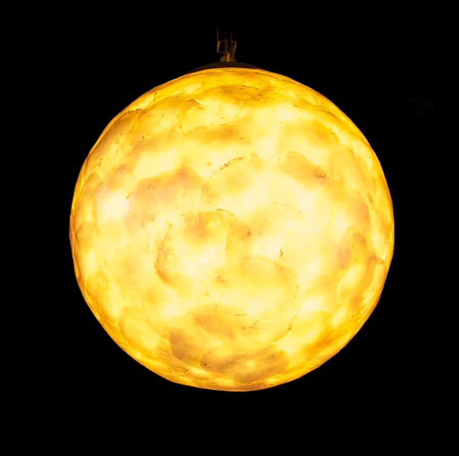 Luminária decorativa esférica de vidro acesa contra fundo escuro