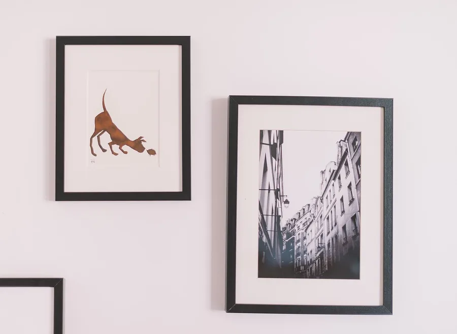 Composição de quadros decorativos com molduras pretas em uma parede clara