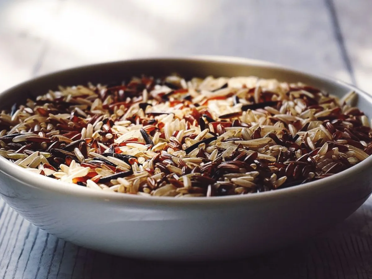 Arroz cru em uma tigela branca sobre uma mesa de madeira
