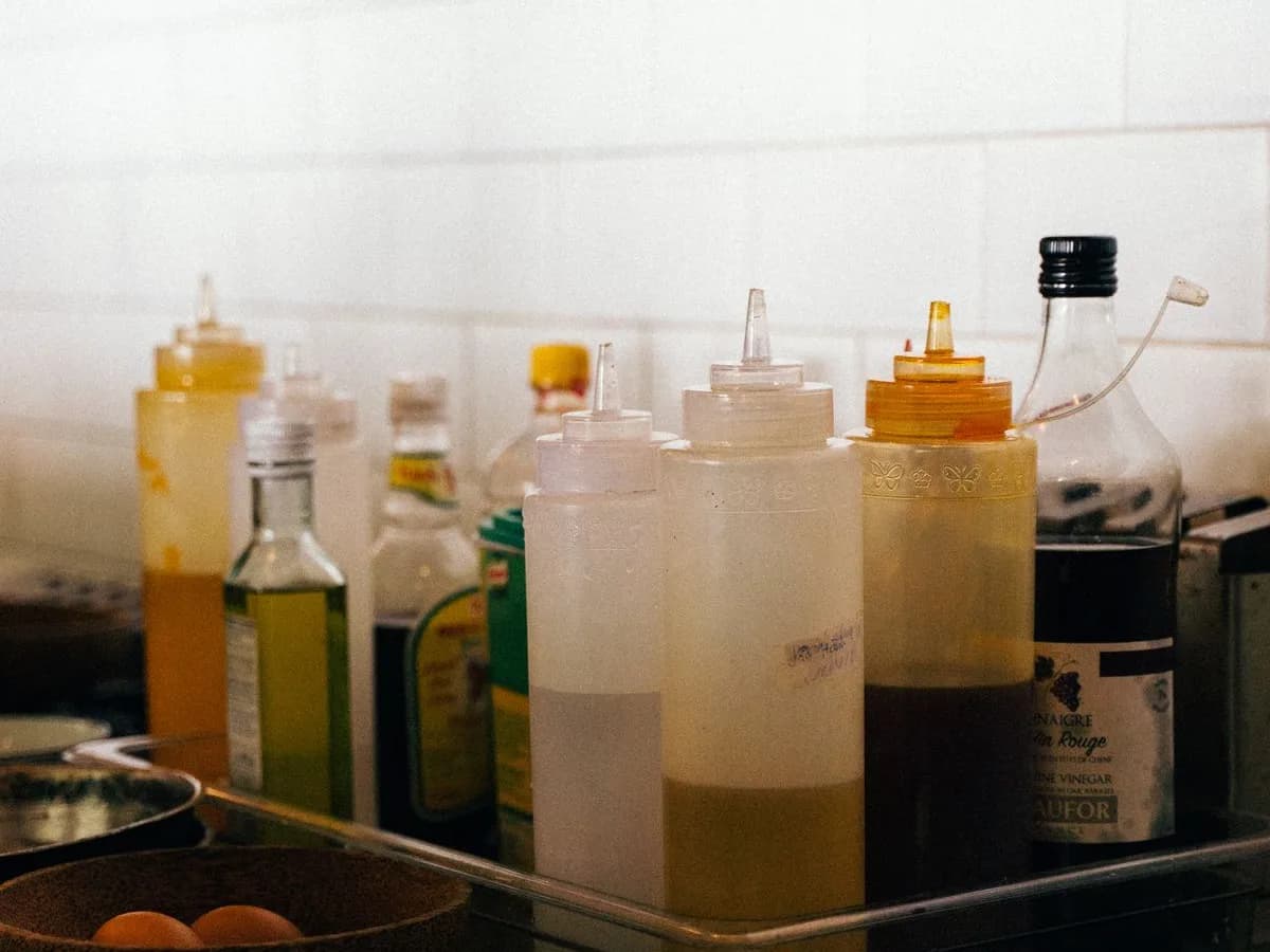 Garrafas de óleos culinários e condimentos organizadas em uma bandeja de cozinha