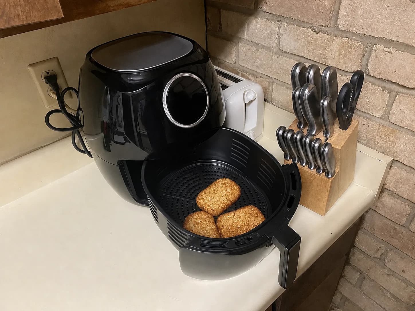 Air fryer sem marca com cesta aberta sobre uma bancada