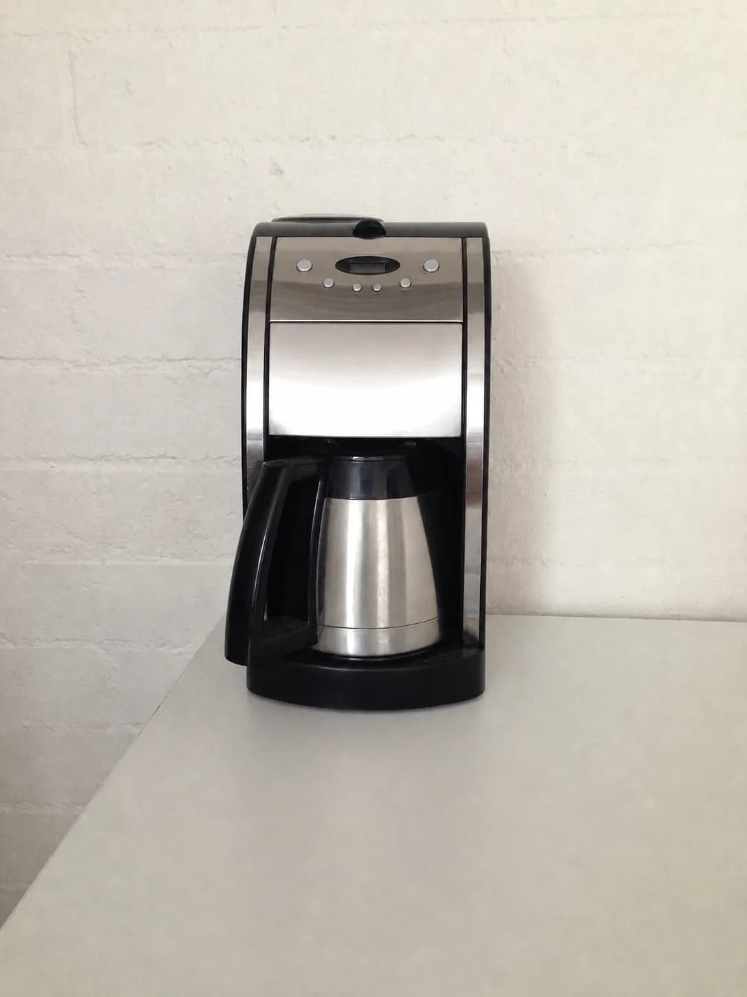 Cafeteira elétrica sem marca fotografada sobre uma mesa