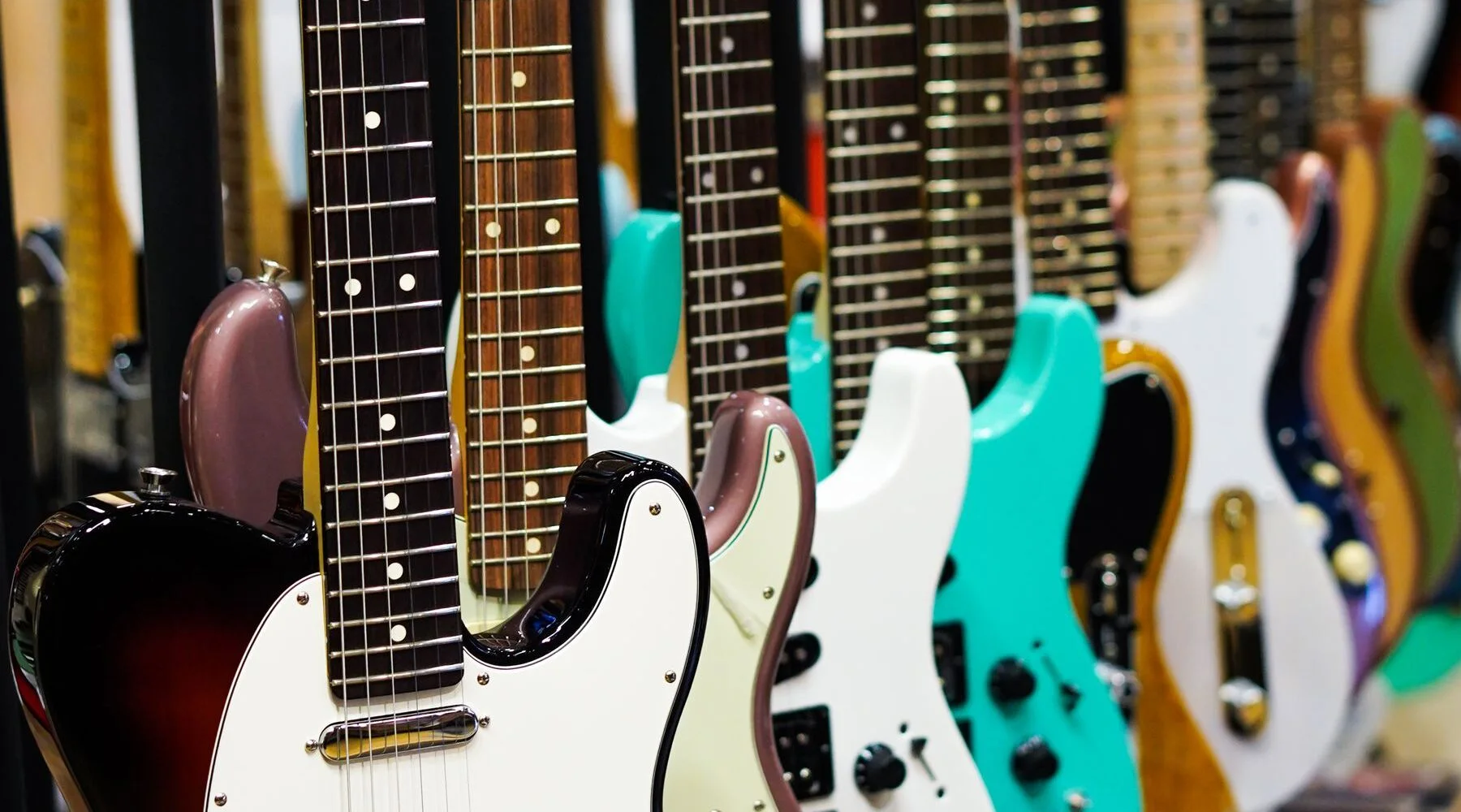 Fileira de guitarras elétricas sem letreiros exposta em uma loja de instrumentos musicais