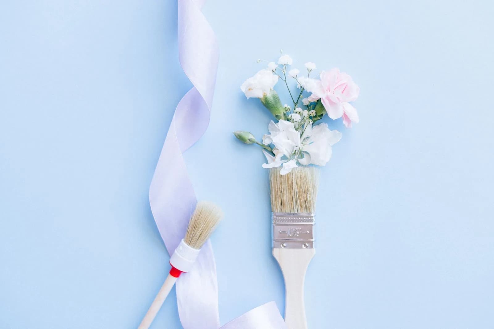 Fita decorativa clara ao lado de pincéis em uma composição de artesanato