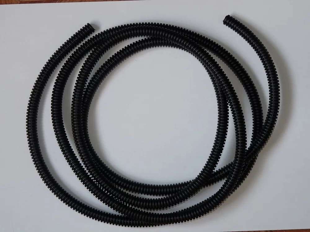 Conduíte elétrico corrugado preto enrolado, sem marca visível
