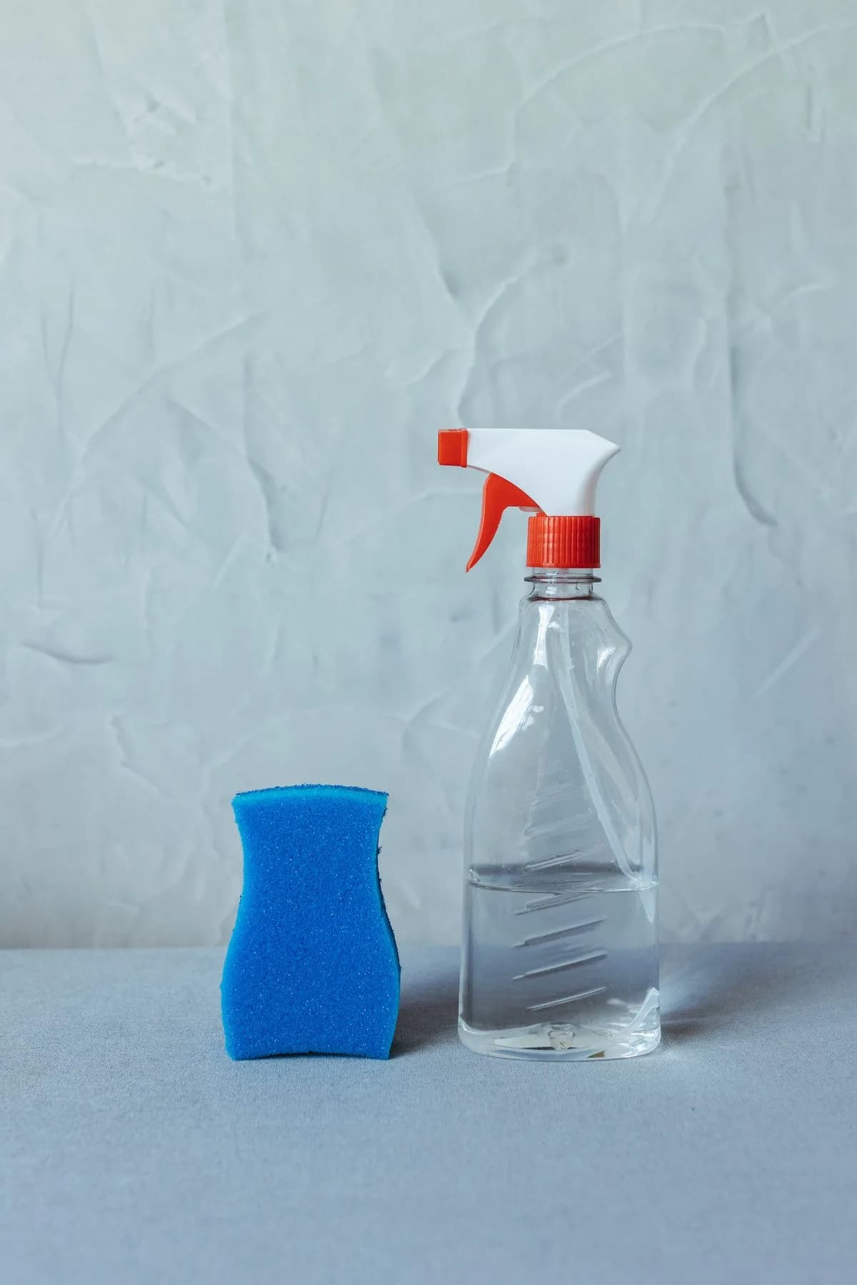 Esponja azul e borrifador de limpeza sobre uma superfície