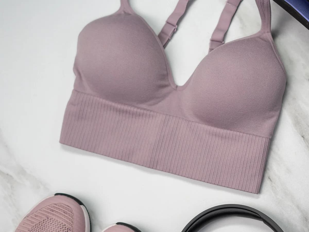 Top fitness rosa disposto em flat lay junto a tapete e acessórios