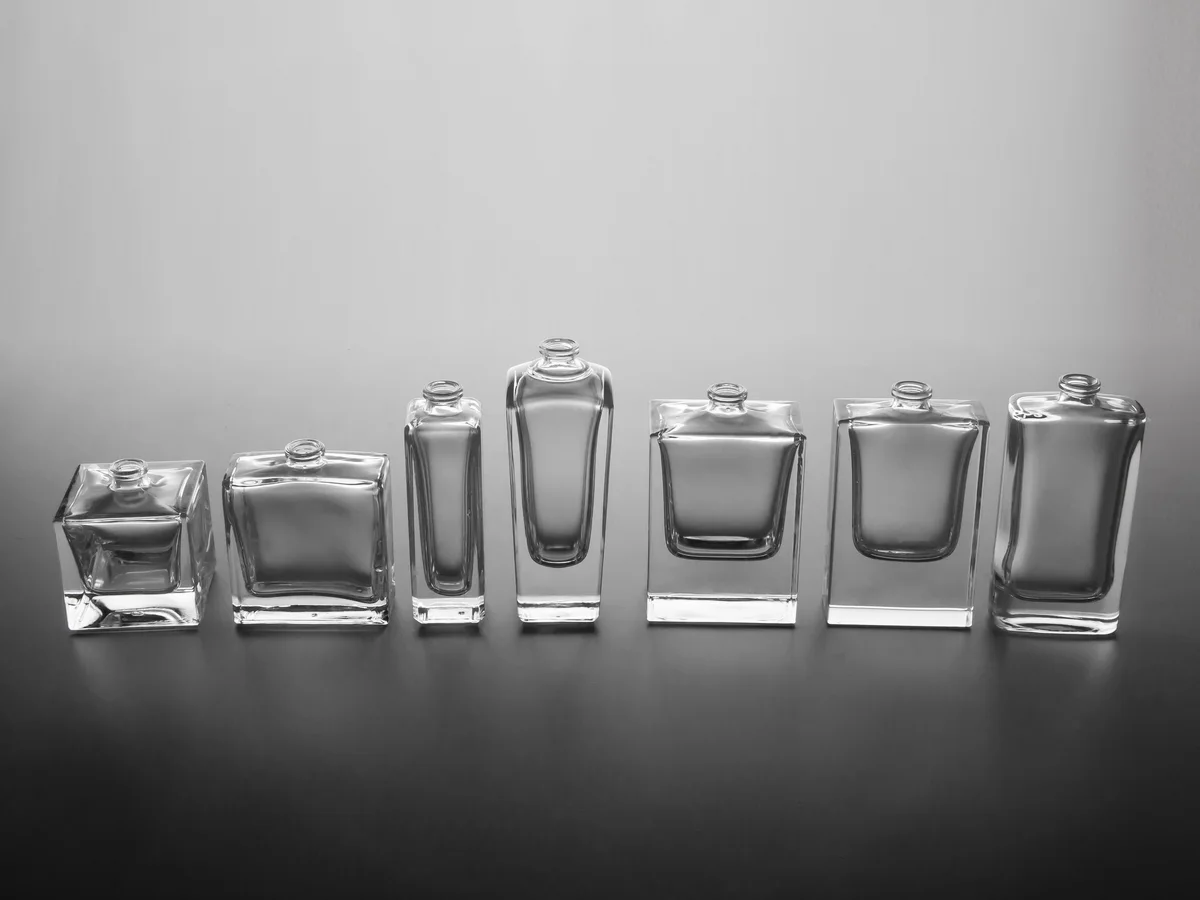Fileira de frascos transparentes de perfume em formatos variados