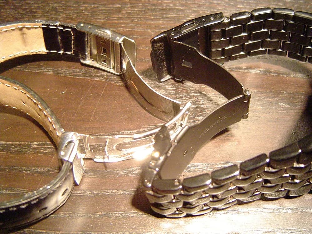 Pulseiras de relógio abertas com fechos visíveis sobre madeira
