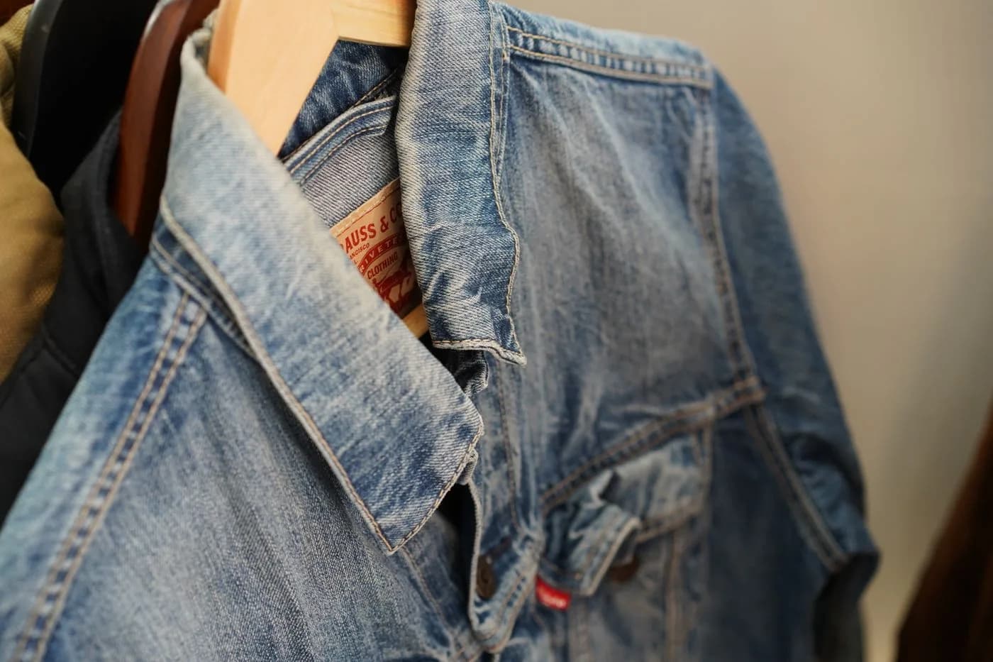 Jaqueta jeans azul pendurada em cabide de madeira