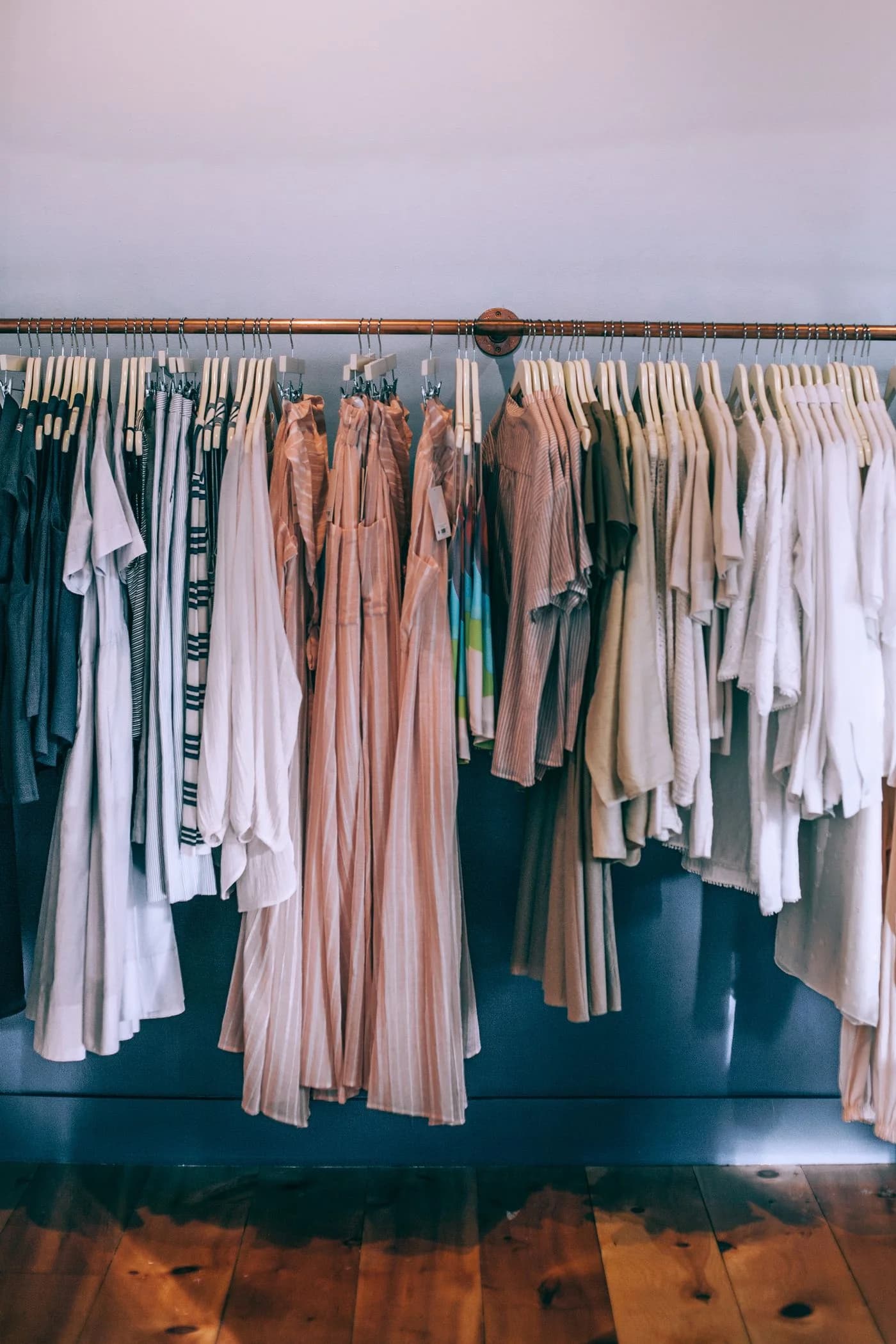 Arara de loja com vestidos, camisas e camisetas organizados por cor