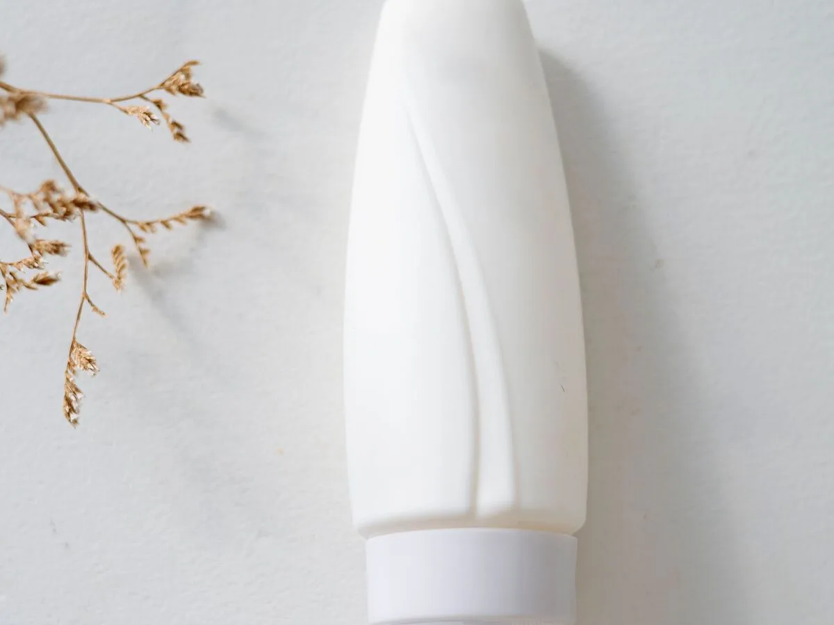 Frasco branco de cosmético corporal sem rótulo sobre fundo claro