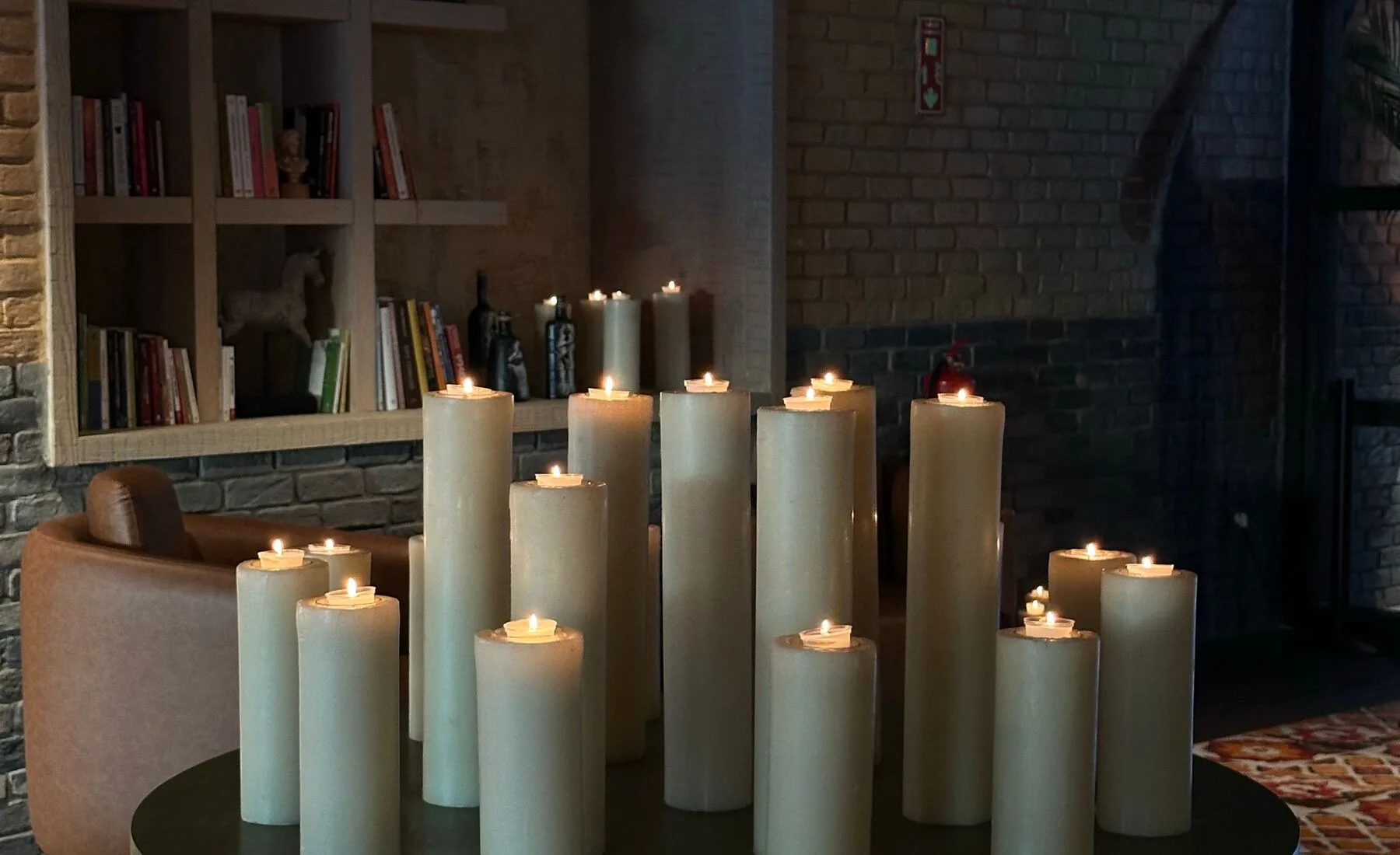 Estante discreta com velas acesas e objetos neutros em uma sala sem pessoas