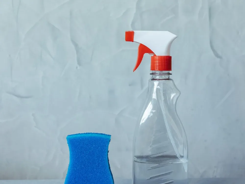 Frasco borrifador transparente e esponja azul sem rótulo visível