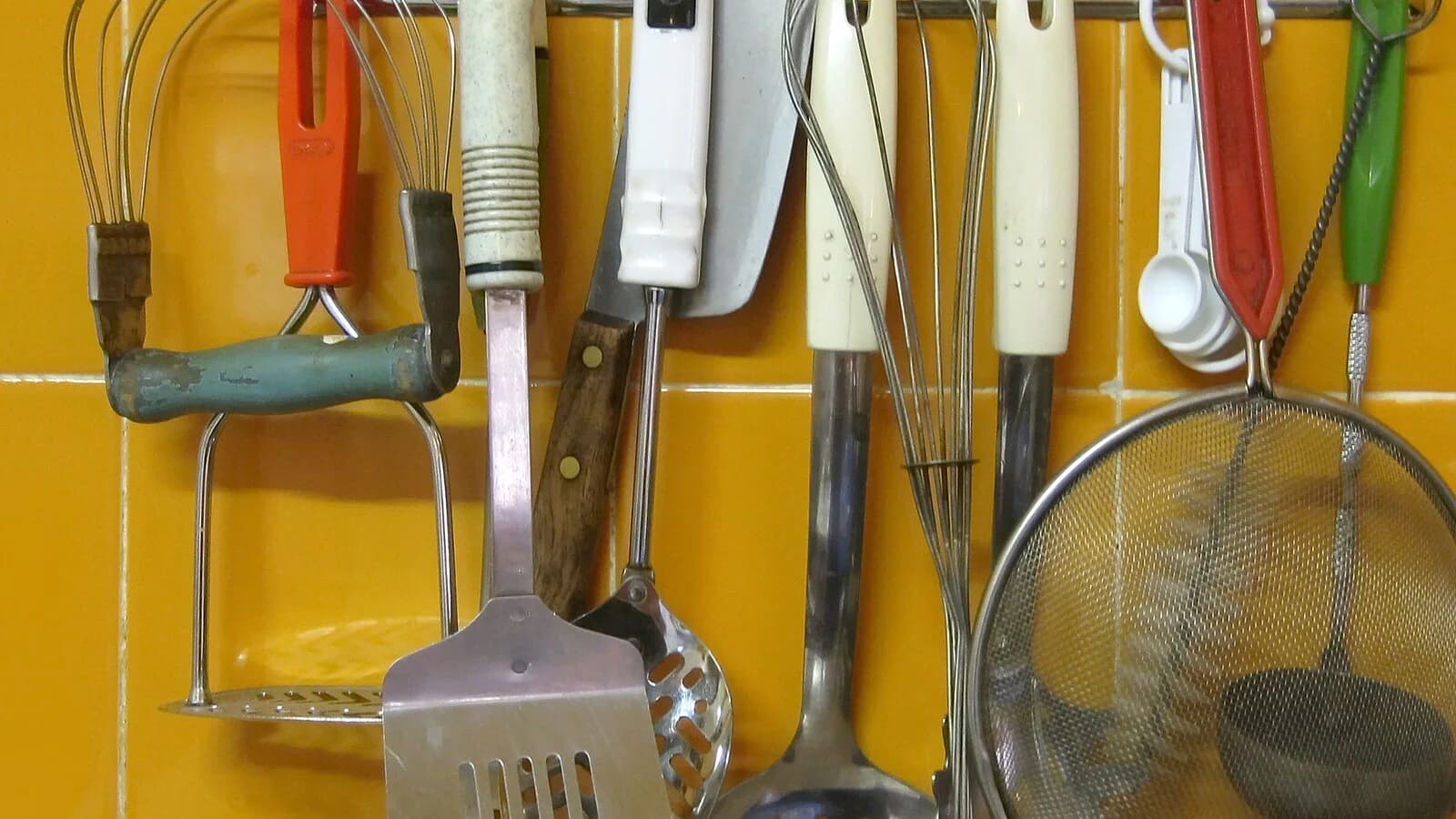 Exposição contemporânea de utensílios domésticos em uma parede de cozinha, sem pessoas ou marcas