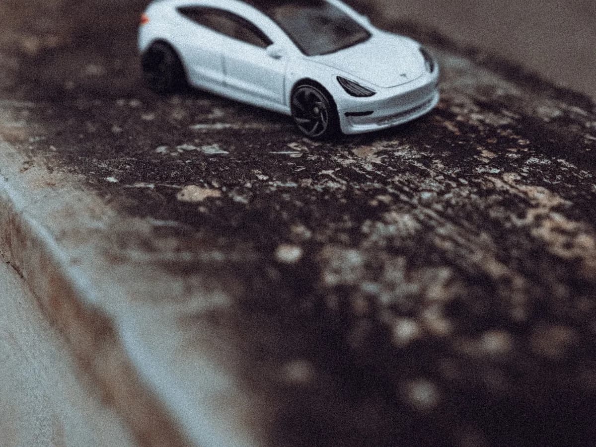 Carrinho de brinquedo branco fotografado sobre uma superfície escura