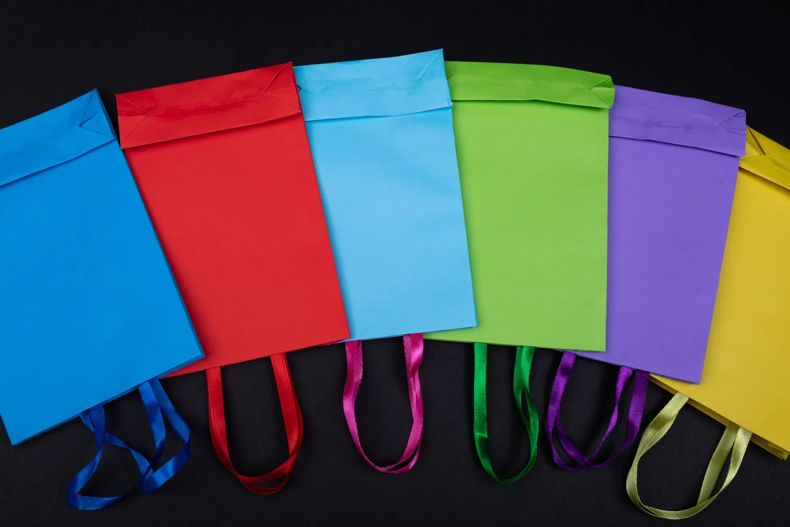 Sacolas de papel coloridas com alças organizadas lado a lado