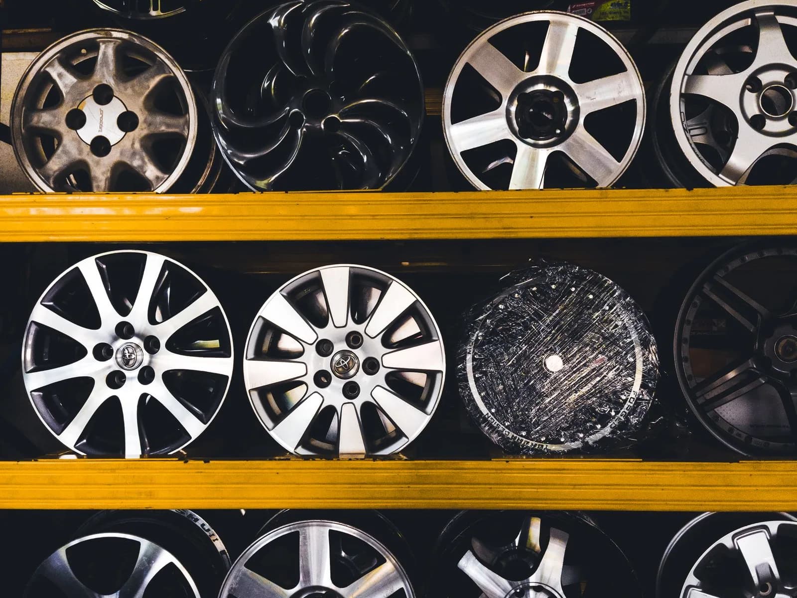 Exposição de rodas e calotas de diferentes desenhos em prateleiras de uma loja de acessórios automotivos