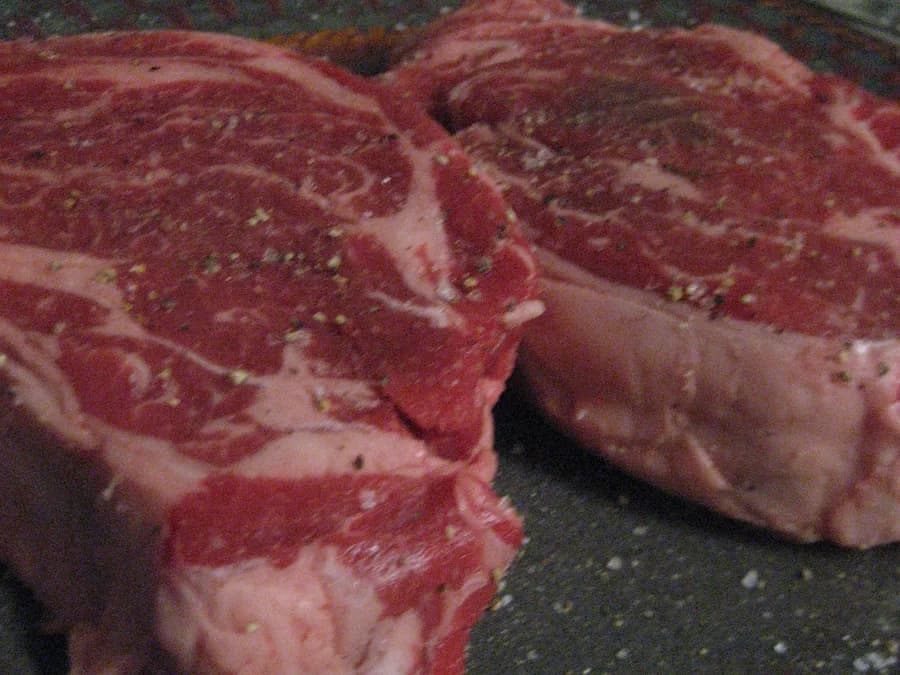 Bifes e cortes bovinos crus vistos de perto em uma superfície escura