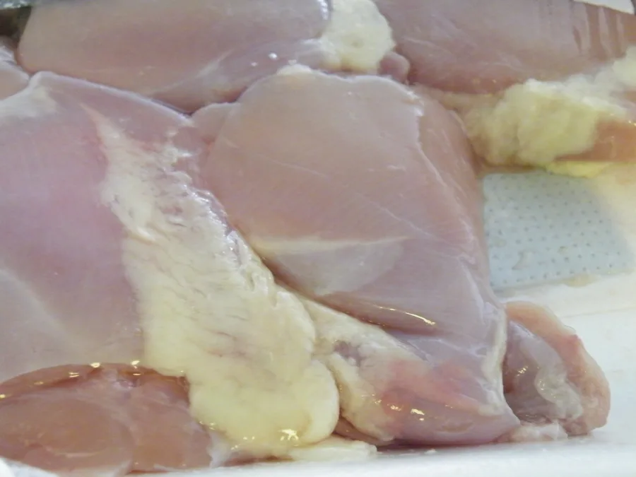 Pedaços crus de coxa e sobrecoxa de frango em uma bandeja