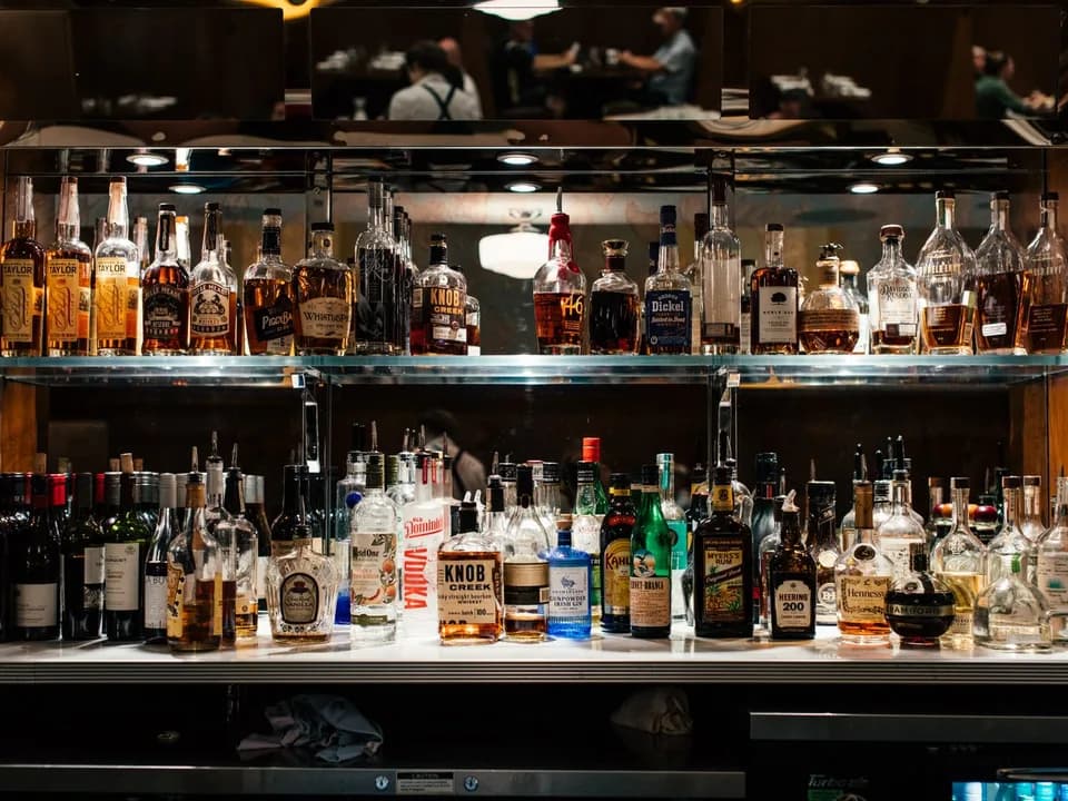 Prateleiras iluminadas com garrafas de uísque, gin, vodca, rum e outros destilados