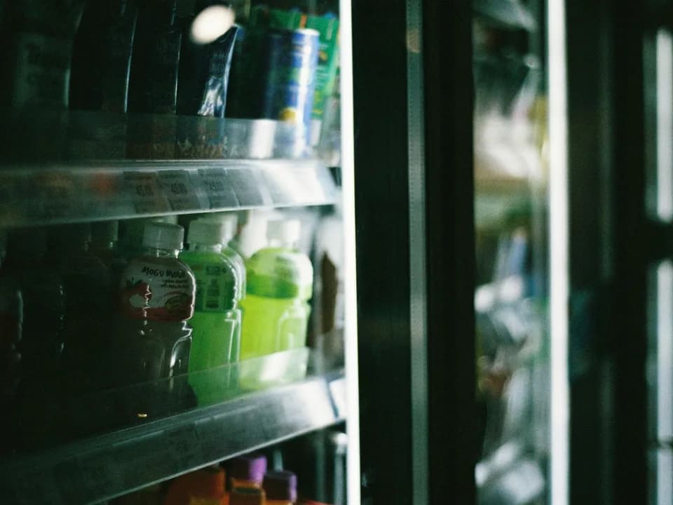 Bebidas em garrafas e latas organizadas em um refrigerador