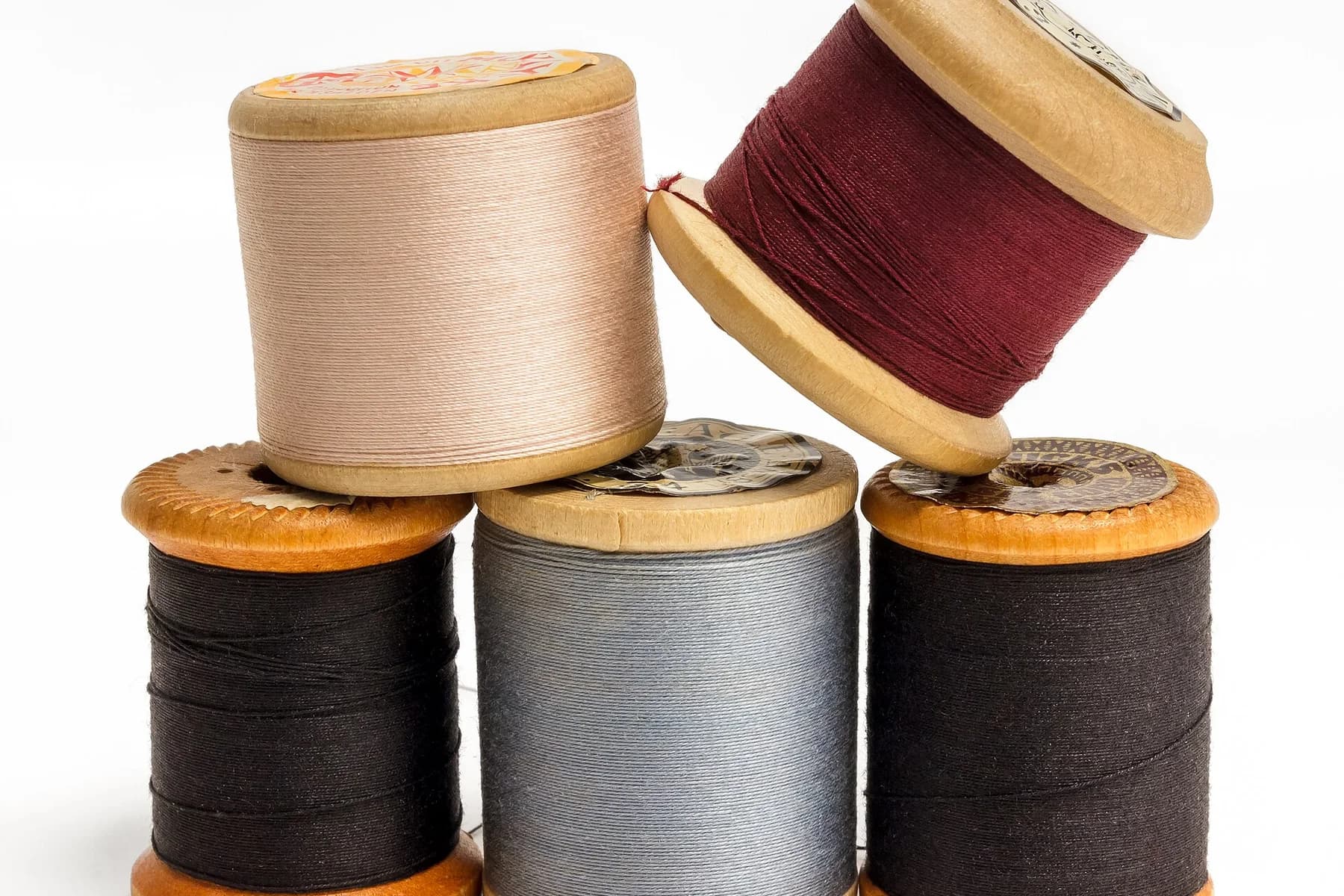 Carretéis de linha em várias cores sobre fundo claro, sem letreiro ou marca dominante