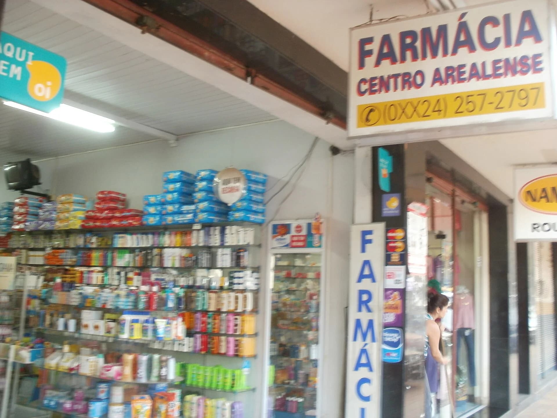 Fachada e vitrine de farmácia brasileira com produtos de saúde expostos