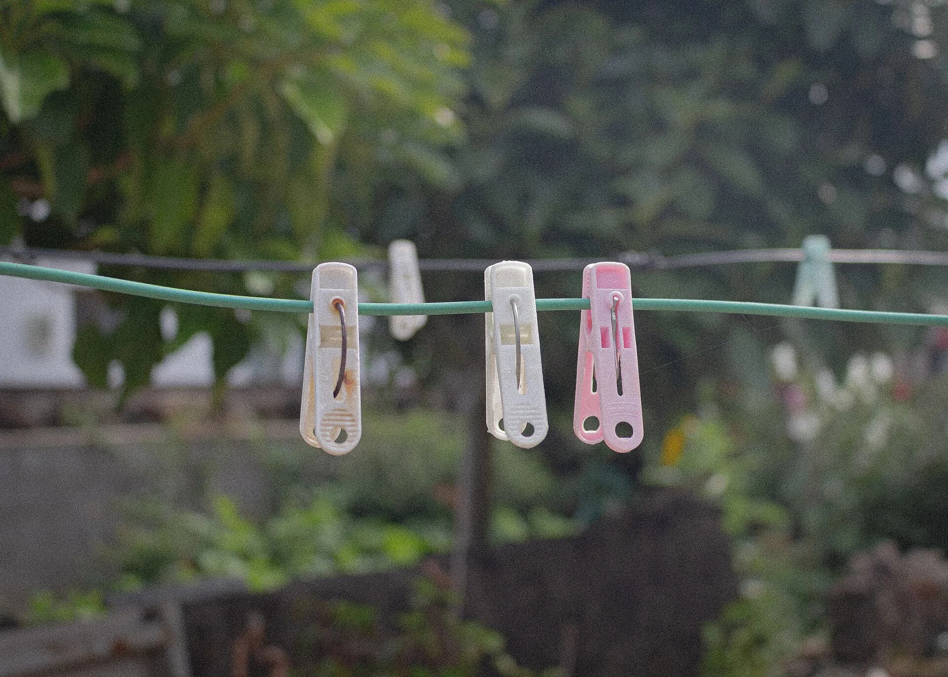 Pregadores de roupa claros e coloridos presos em um varal, representando a família de utilidades