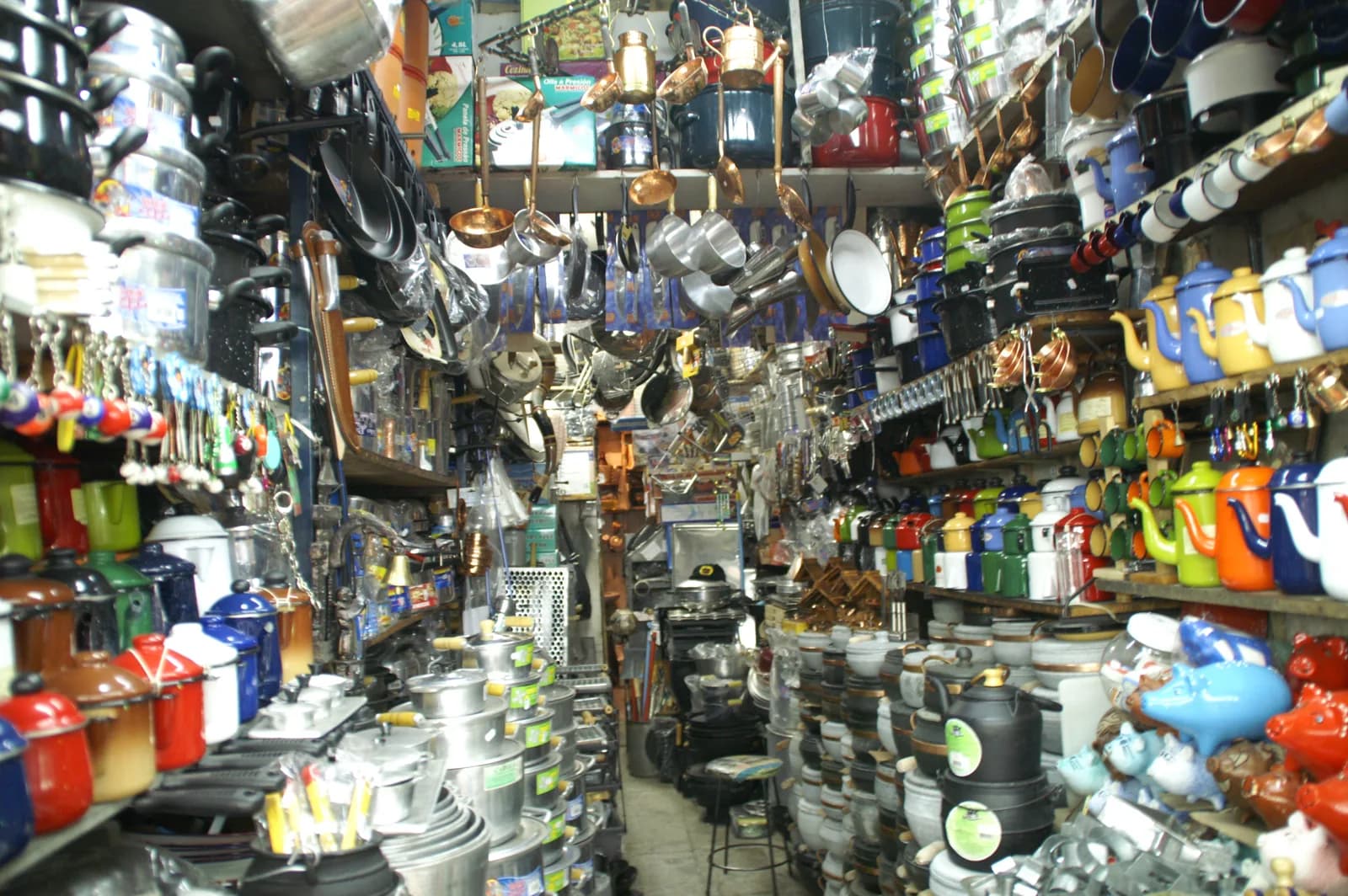 Interior de loja brasileira com panelas, chaleiras, canecas e utensílios domésticos organizados em prateleiras