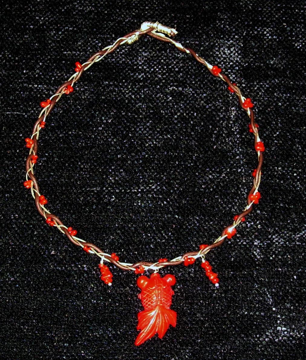Colar artesanal de cordão vermelho sobre fundo escuro