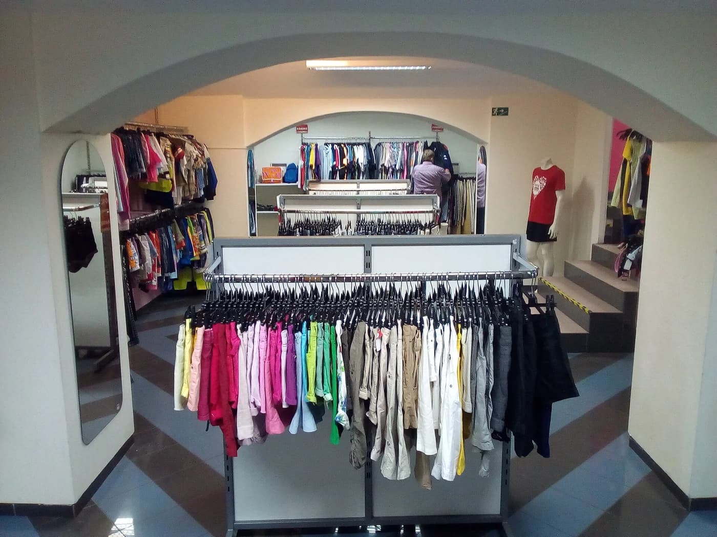 Araras com camisas e outras roupas usadas dentro de uma loja de segunda mão