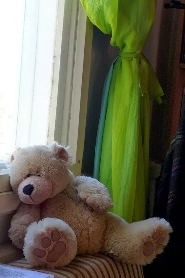 Urso de pelúcia sentado ao lado de uma janela