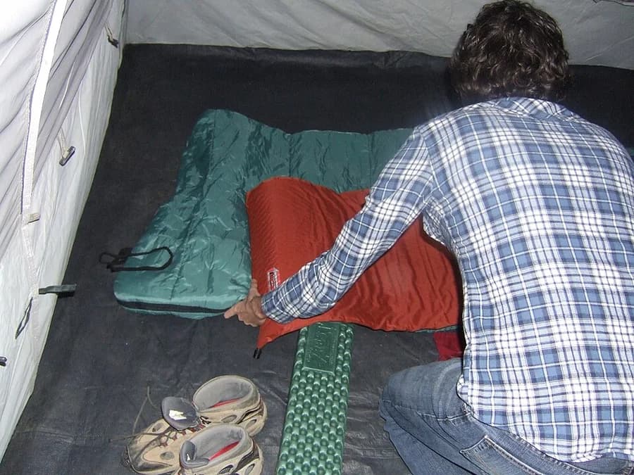 Saco de dormir sendo ajustado dentro de uma barraca
