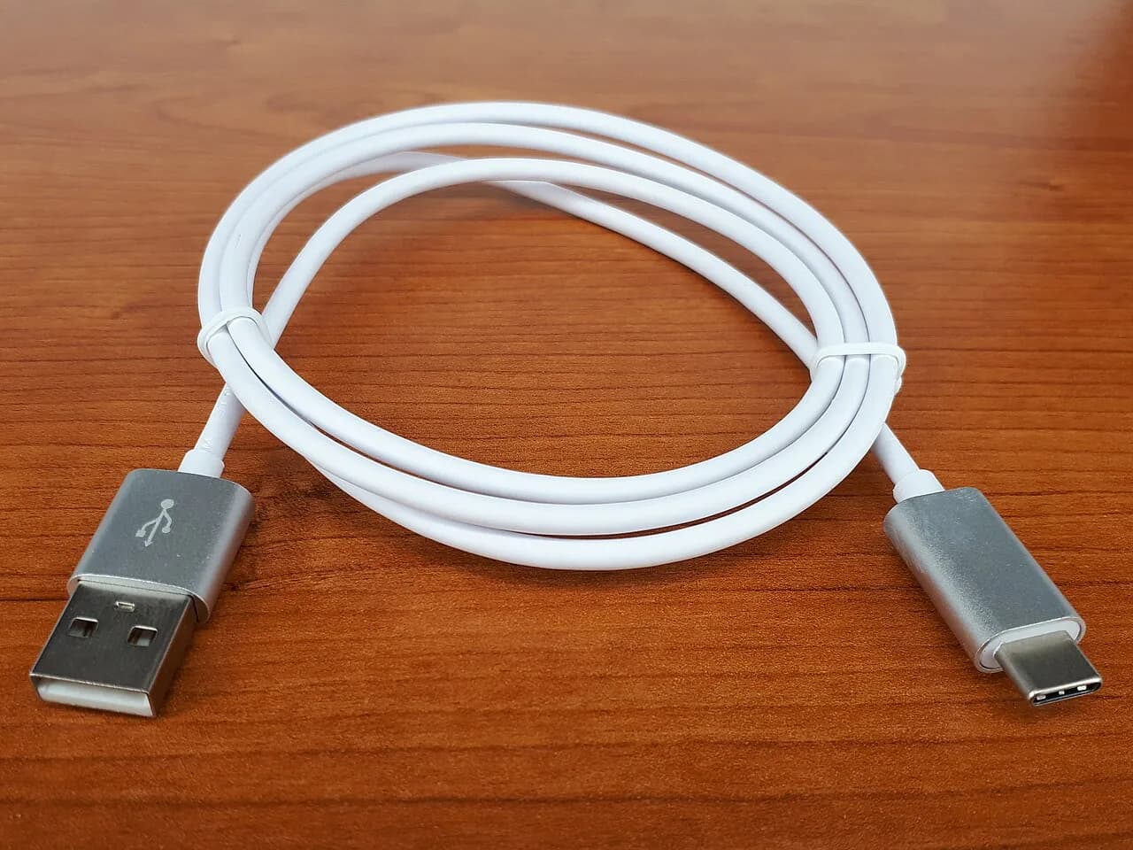 Cabo branco com conector USB-C fotografado sobre madeira
