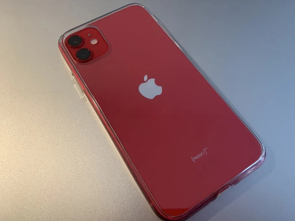 iPhone 11 vermelho fotografado sobre uma superfície clara
