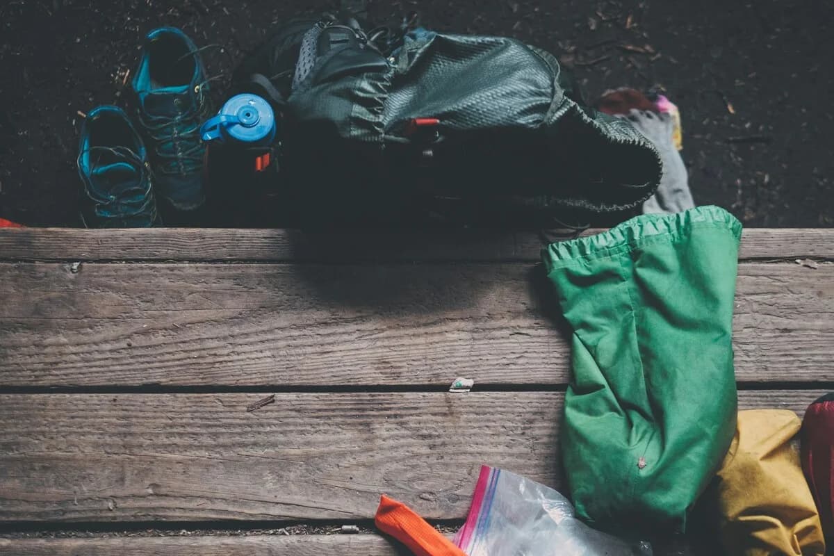 Mochila apoiada sobre uma bancada de madeira ao ar livre