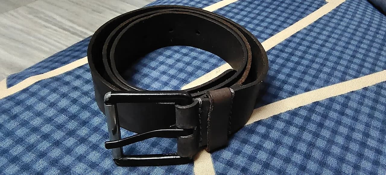 Cinto preto de moda disposto sobre tecido quadriculado