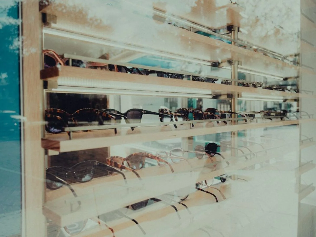 Família de óculos solares organizada em uma vitrine de ótica, sem pessoas ou marcas visíveis