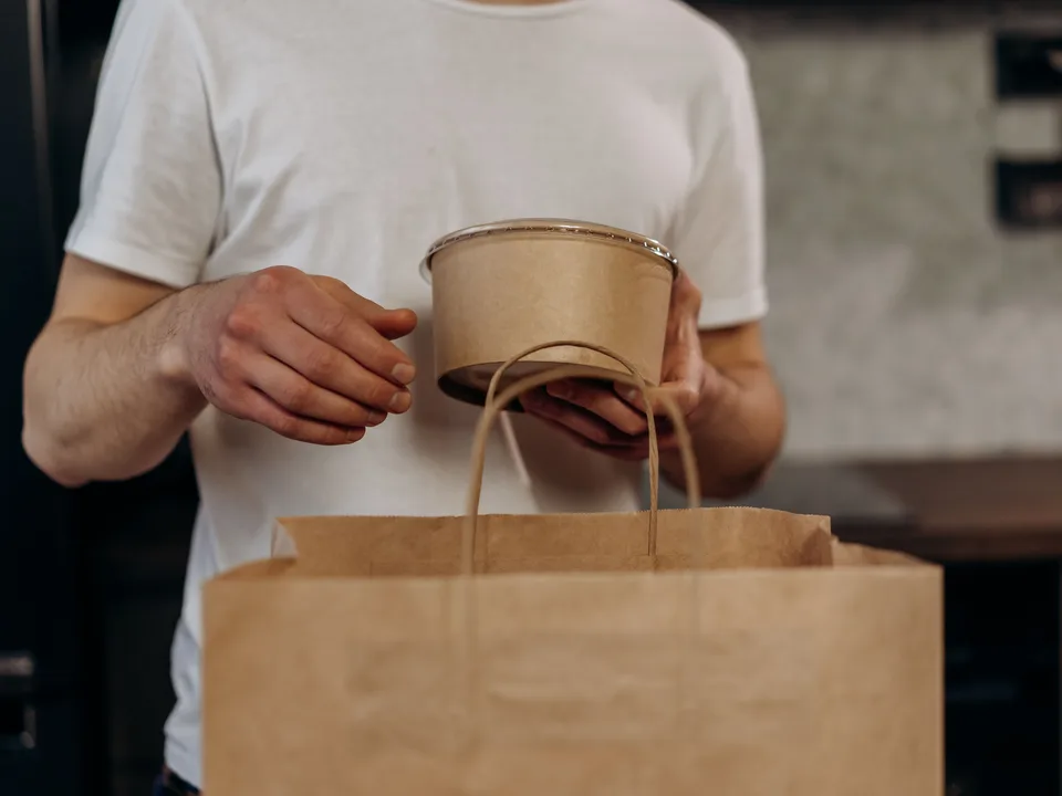 Pessoa segurando embalagem kraft de papel para alimentos
