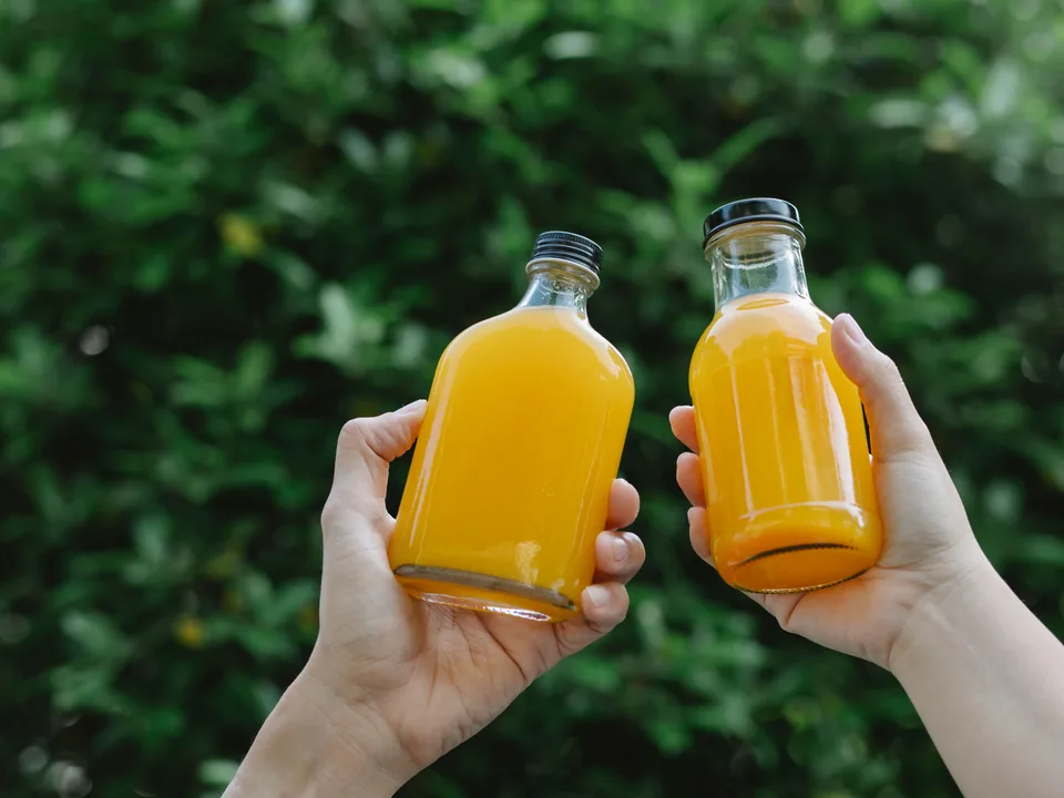 Duas garrafas transparentes com suco de laranja