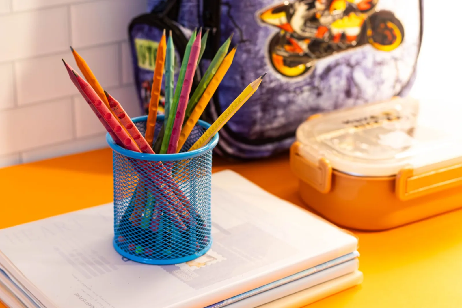 Cadernos, lápis de cor e estojo organizados sobre uma mesa escolar