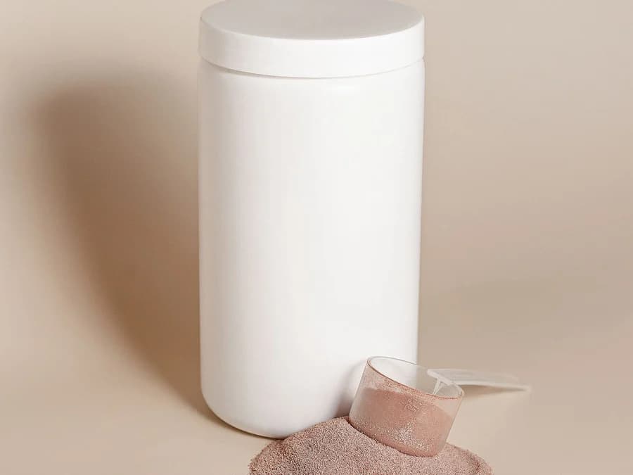Pote branco sem rótulo ao lado de medida transparente e pó rosado
